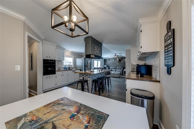 kitchen featuring crown molding, stainless steel fridge with ice dispenser, ceiling fan with notable chandelier, white cabinetry, and a sink