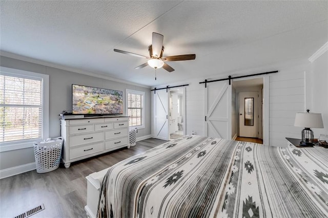 bedroom featuring dark wood-style floors, visible vents, multiple windows, and a barn door