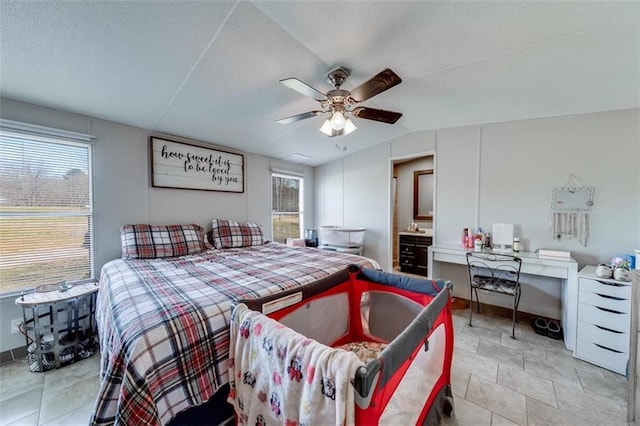 bedroom featuring ensuite bath, a textured ceiling, a ceiling fan, and vaulted ceiling