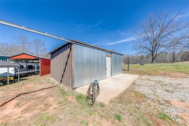 view of outbuilding featuring an outdoor structure, a carport, and dirt driveway