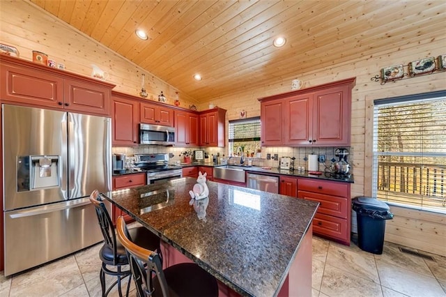 kitchen featuring wood walls, lofted ceiling, appliances with stainless steel finishes, wooden ceiling, and a sink