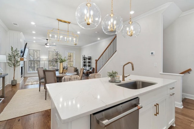 kitchen featuring sink, decorative light fixtures, dishwasher, a kitchen island with sink, and white cabinets