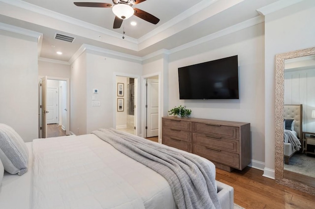 bedroom featuring wood-type flooring, ornamental molding, a raised ceiling, and ceiling fan