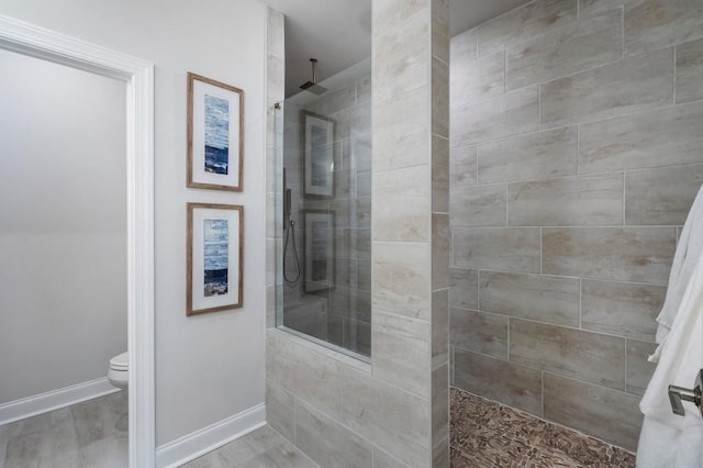 bathroom with hardwood / wood-style floors, toilet, and tiled shower