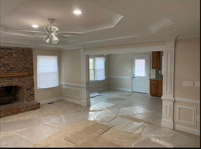 interior space with a raised ceiling, ceiling fan, and a fireplace