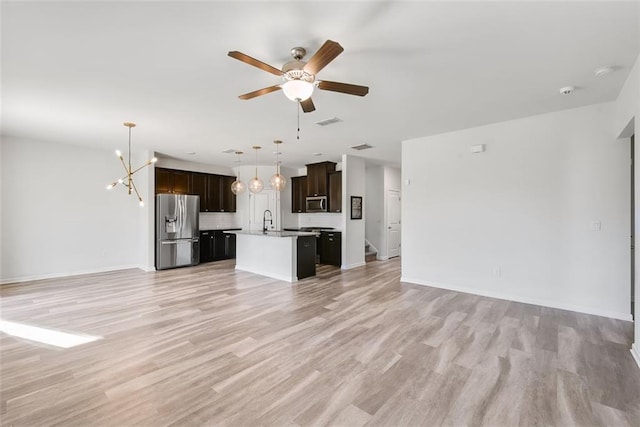 unfurnished living room featuring ceiling fan with notable chandelier, light hardwood / wood-style flooring, and sink