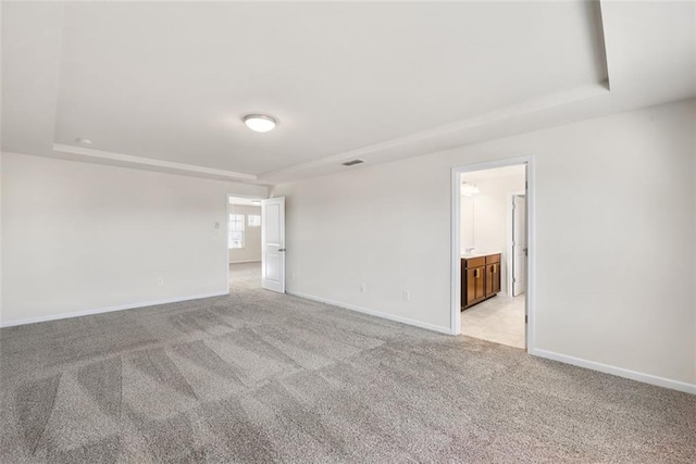 carpeted empty room featuring a tray ceiling