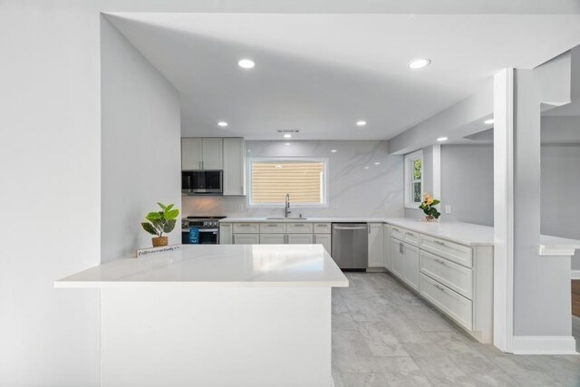 kitchen with kitchen peninsula, stainless steel appliances, sink, and decorative backsplash