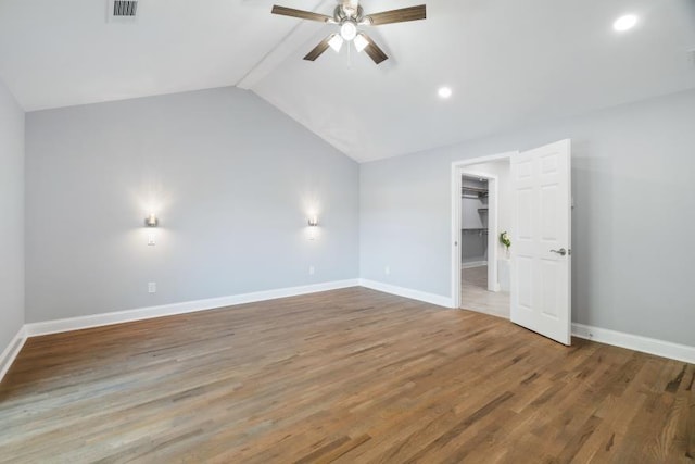 unfurnished bedroom with ceiling fan, a spacious closet, wood-type flooring, a closet, and vaulted ceiling