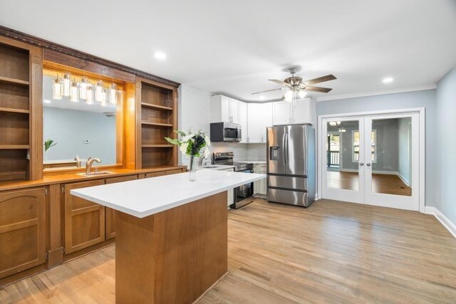 kitchen with french doors, stainless steel appliances, a kitchen island, ceiling fan, and light hardwood / wood-style flooring