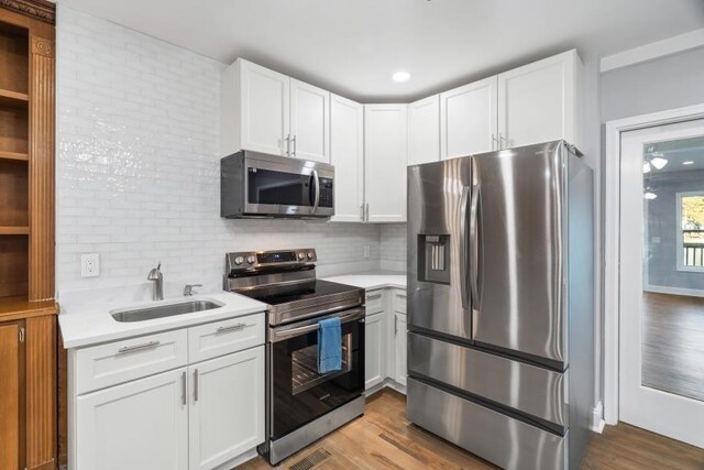 kitchen featuring white cabinetry, stainless steel appliances, light hardwood / wood-style floors, and sink