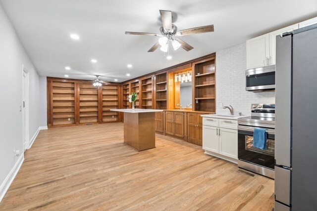 kitchen featuring stainless steel appliances, light hardwood / wood-style floors, white cabinetry, ceiling fan, and a kitchen island