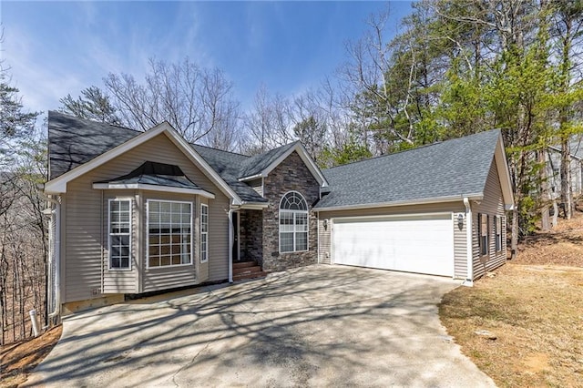 ranch-style house with stone siding, a shingled roof, an attached garage, and driveway