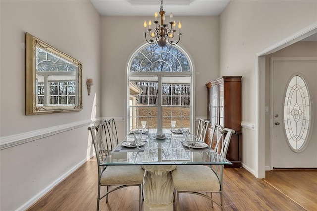 dining room with a chandelier, baseboards, and wood finished floors