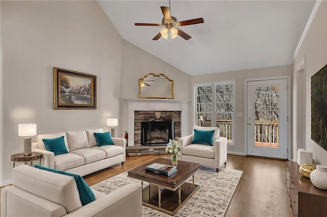 living room with ceiling fan, high vaulted ceiling, wood finished floors, and a stone fireplace