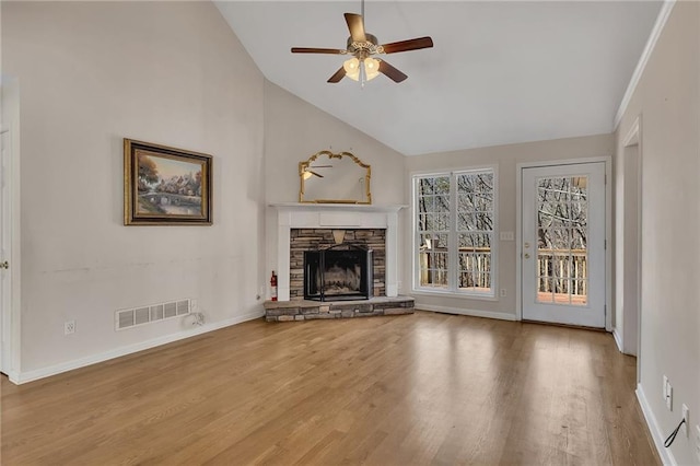 unfurnished living room featuring lofted ceiling, ceiling fan, a stone fireplace, wood finished floors, and visible vents