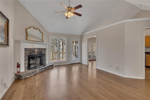 unfurnished living room with lofted ceiling, ceiling fan, a fireplace, wood finished floors, and baseboards