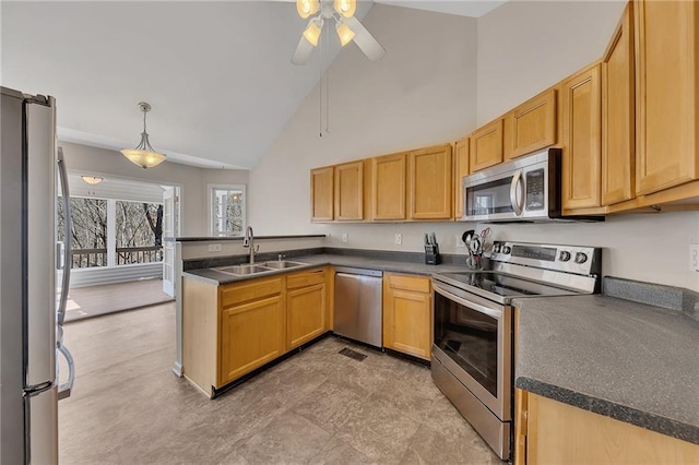 kitchen featuring appliances with stainless steel finishes, dark countertops, a sink, and a peninsula