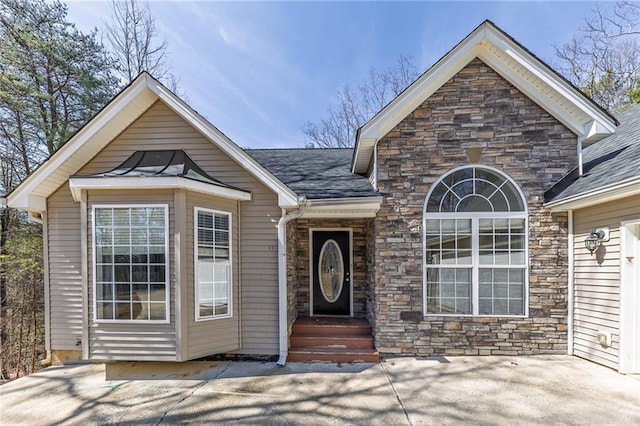 property entrance with stone siding and a shingled roof