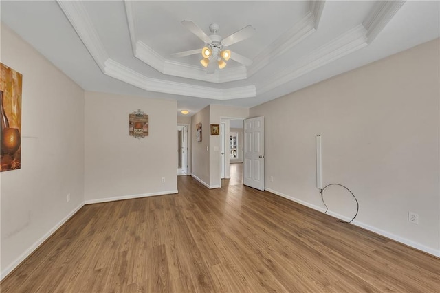 spare room with crown molding, a tray ceiling, ceiling fan, and wood finished floors