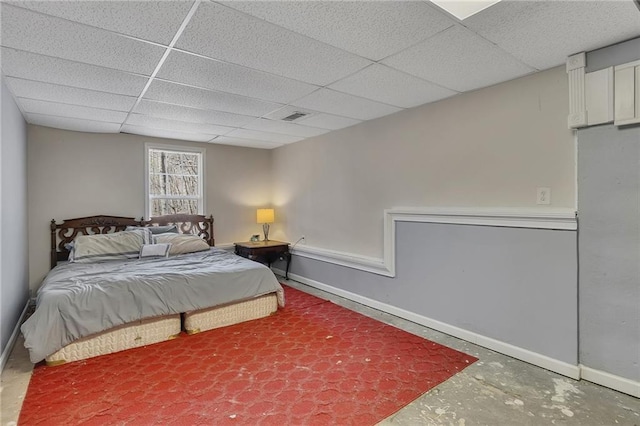 bedroom featuring a paneled ceiling, baseboards, concrete floors, and visible vents