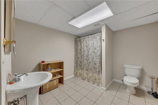 full bathroom with curtained shower, a drop ceiling, tile patterned flooring, and toilet