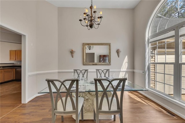 dining area with dark wood-style floors, baseboards, and an inviting chandelier