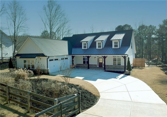 view of front facade featuring metal roof, a garage, fence, driveway, and a standing seam roof