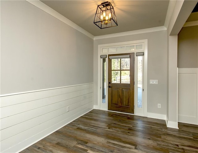 foyer with dark wood-style floors, a wainscoted wall, an inviting chandelier, and crown molding