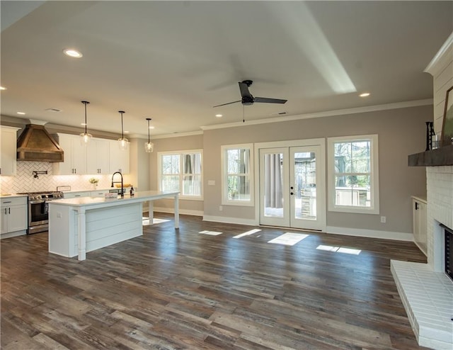 kitchen with a fireplace, tasteful backsplash, ornamental molding, stainless steel range with gas stovetop, and premium range hood