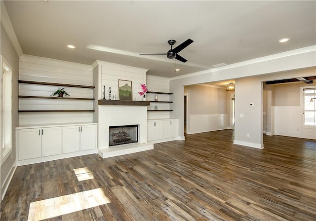 unfurnished living room featuring dark wood-type flooring, a brick fireplace, a ceiling fan, and recessed lighting