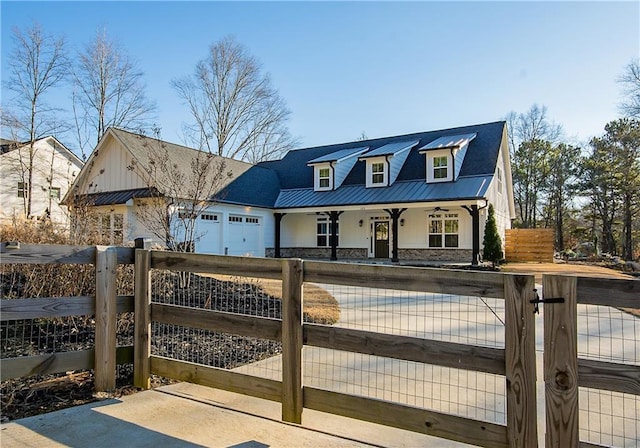 view of front of property with a garage, stone siding, a fenced front yard, and metal roof