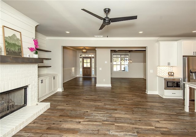 unfurnished living room featuring ceiling fan, recessed lighting, a brick fireplace, dark wood-style floors, and crown molding