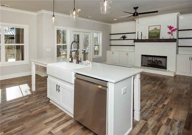 kitchen with visible vents, dishwasher, crown molding, a brick fireplace, and a sink