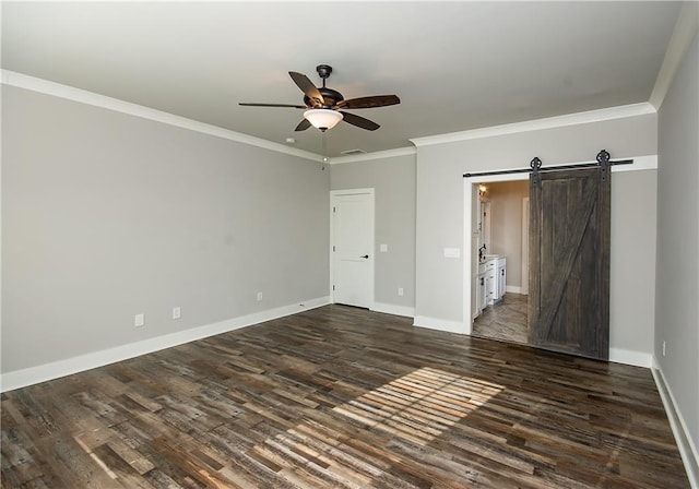 unfurnished bedroom featuring baseboards, a barn door, dark wood-style flooring, and crown molding