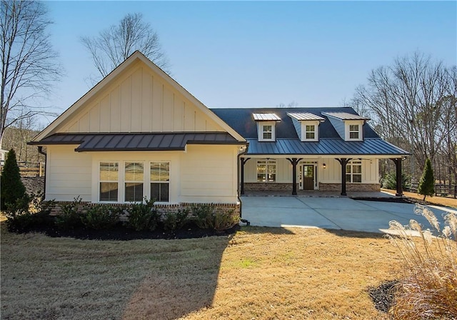 view of front facade featuring brick siding, covered porch, board and batten siding, a standing seam roof, and metal roof