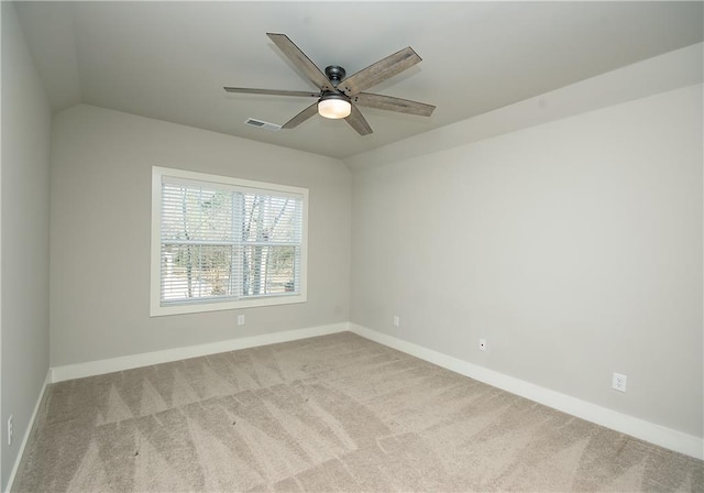 carpeted spare room with lofted ceiling, baseboards, and visible vents