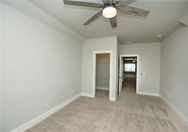 unfurnished bedroom with light carpet, baseboards, a ceiling fan, a spacious closet, and a closet