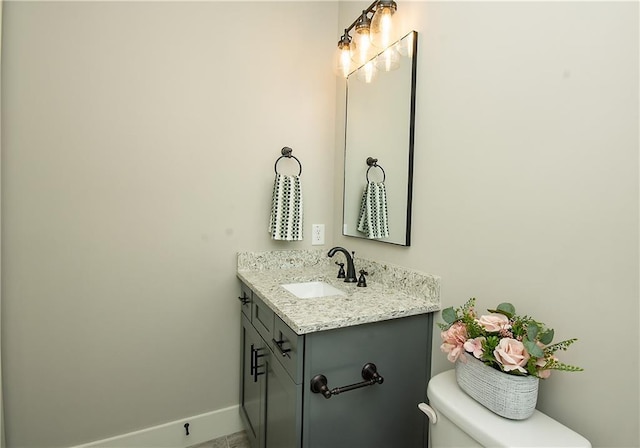 bathroom featuring vanity, toilet, and baseboards