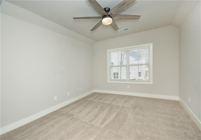 empty room with light colored carpet, visible vents, vaulted ceiling, ceiling fan, and baseboards