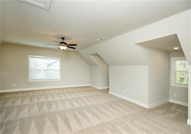 additional living space featuring visible vents, baseboards, light colored carpet, ceiling fan, and vaulted ceiling