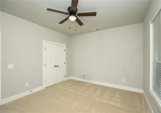 interior space with a ceiling fan, visible vents, light carpet, and baseboards