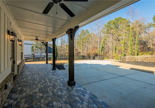 view of patio / terrace featuring fence, a forest view, and ceiling fan