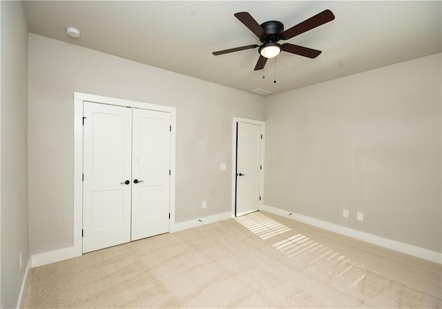 unfurnished bedroom with a closet, light colored carpet, and baseboards