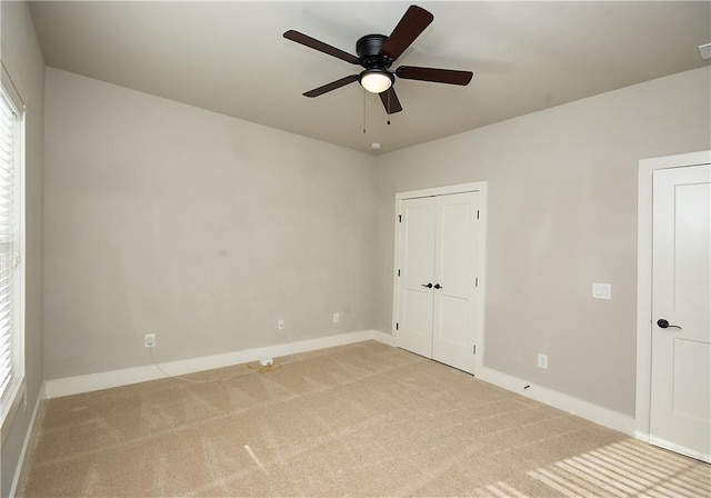 unfurnished bedroom with baseboards, a ceiling fan, and light colored carpet