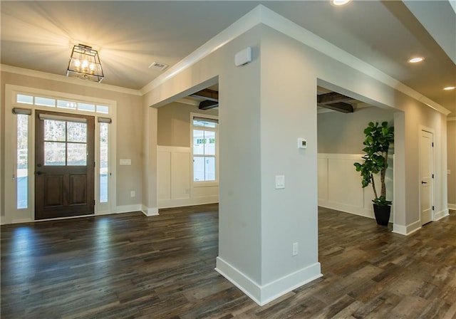 foyer entrance with a wainscoted wall, ornamental molding, and dark wood-type flooring