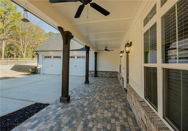 view of patio with concrete driveway, an attached garage, fence, and a ceiling fan