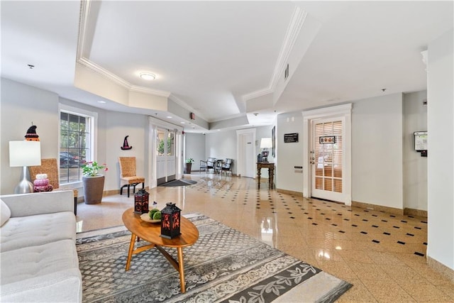 living room featuring granite finish floor, a tray ceiling, crown molding, and baseboards