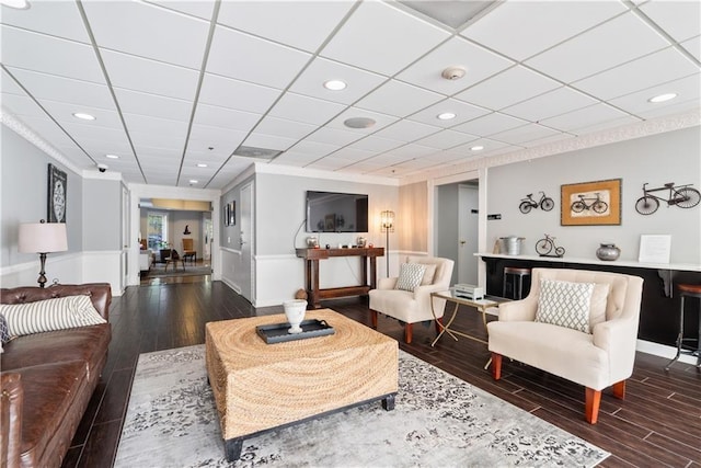 living area featuring crown molding, baseboards, a drop ceiling, recessed lighting, and wood finished floors