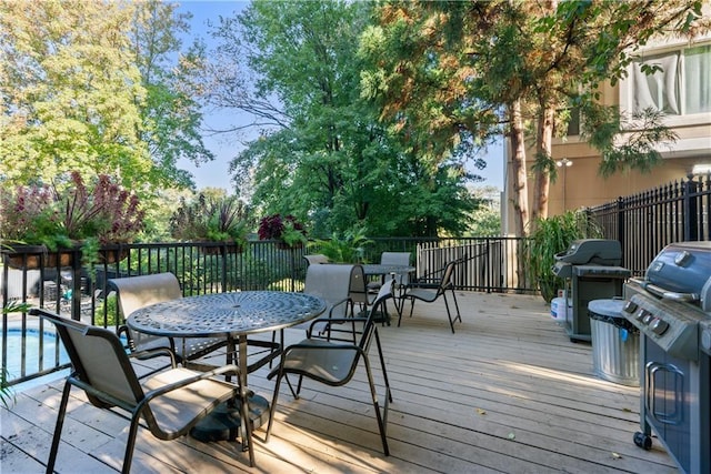 wooden terrace featuring grilling area and a fenced in pool